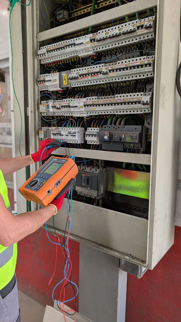 Técnico realizando mediciones en un cuadro eléctrico industrial